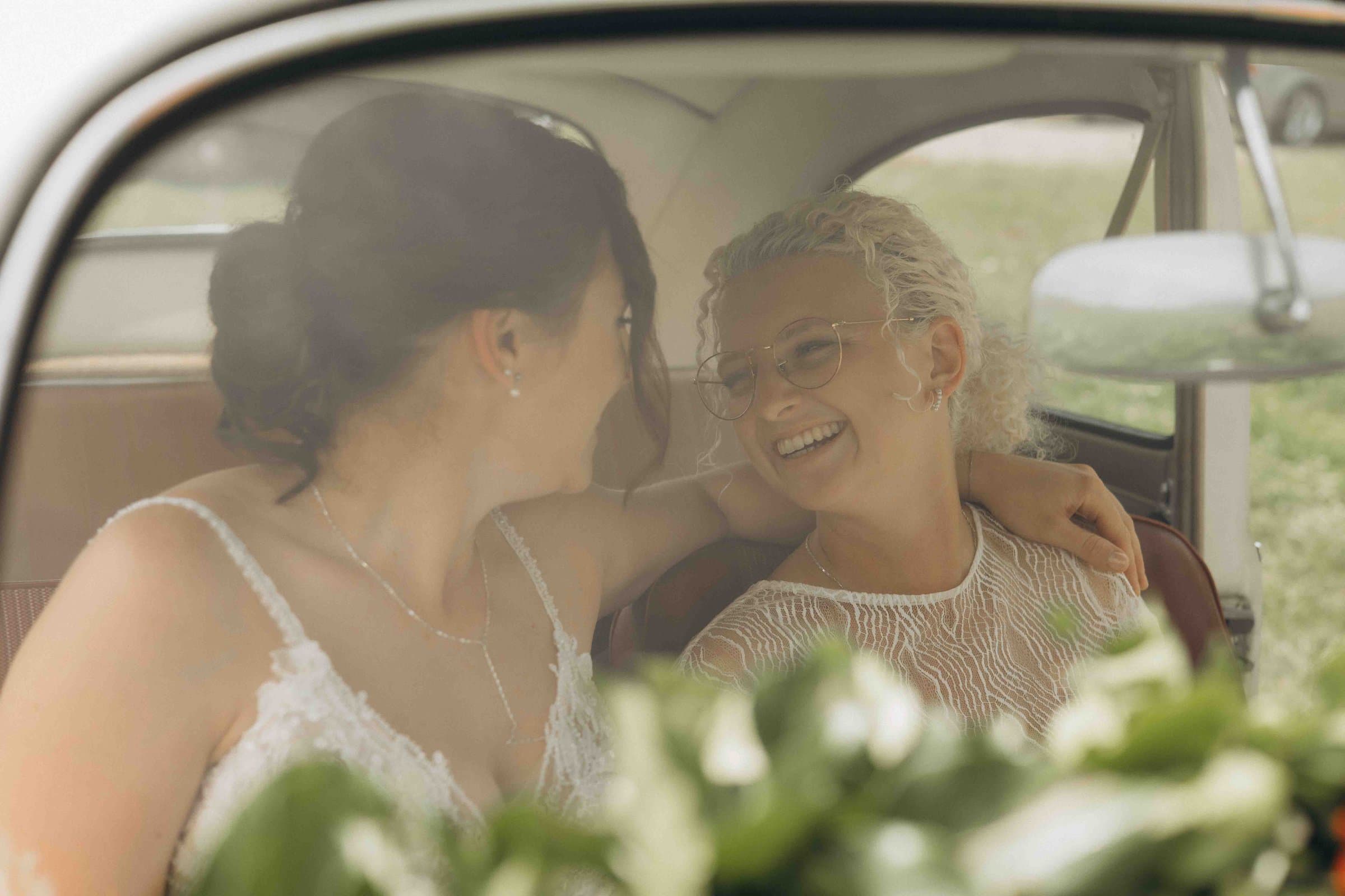 Brautpaar lacht im Oldtimer